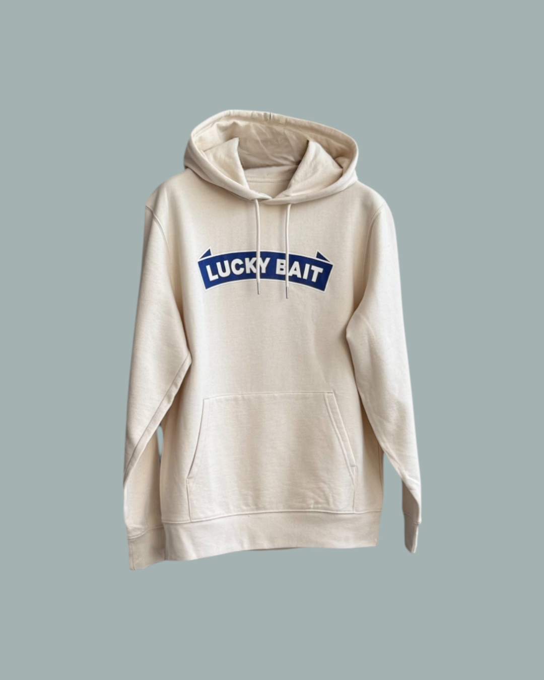 Hoodien Natur har en framficka och en blåvit Lucky Bait logotyp tryckt över bröstet. Visas mot en stålblå bakgrund.