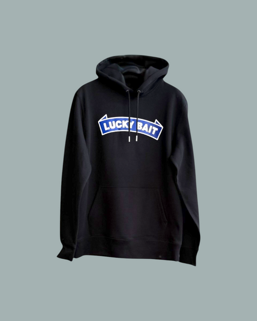 Hoodien Svart har en framficka och en blåvit Lucky Bait logo tryckt över bröstet. Visas mot en stålblå bakgrund.