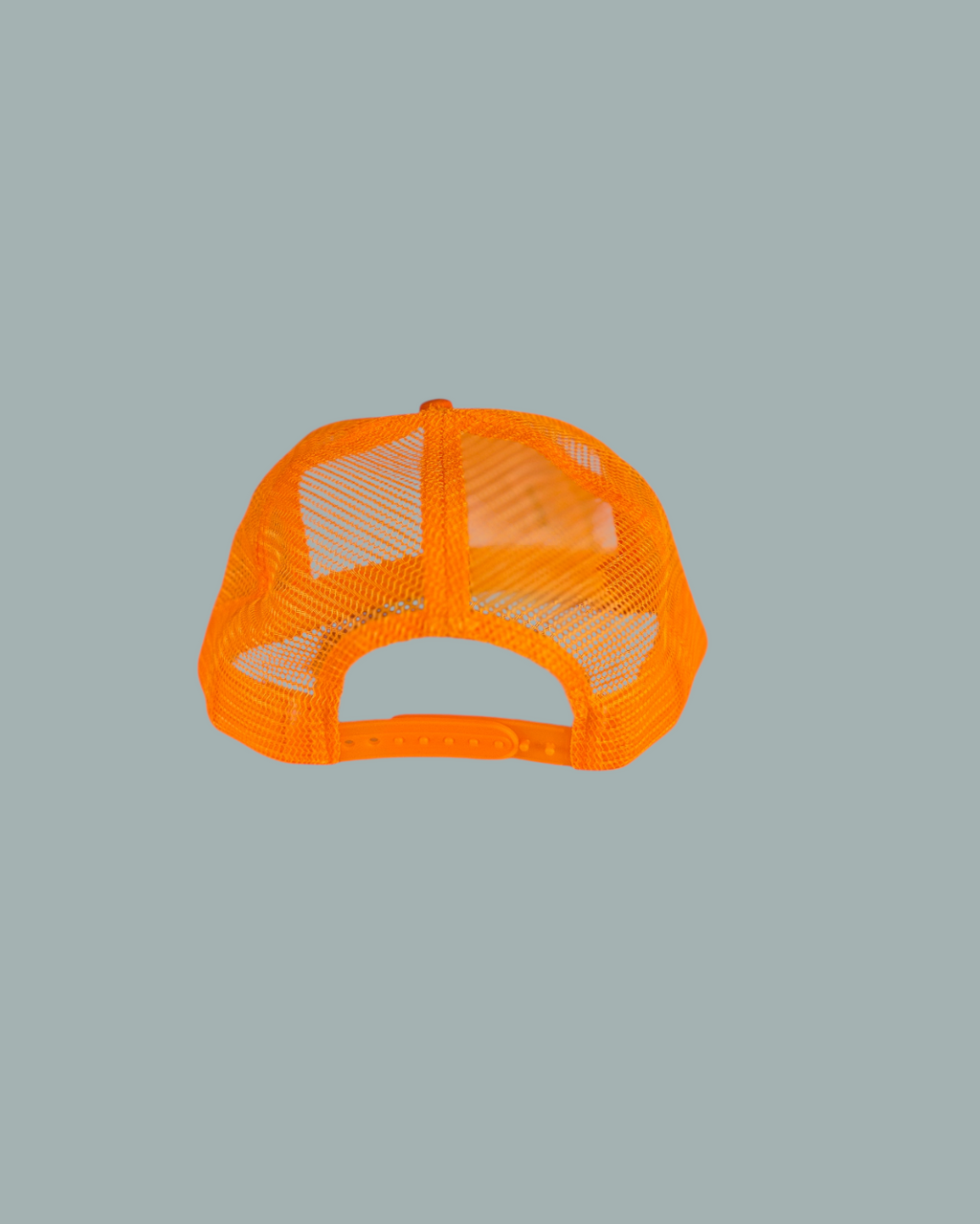 Keps Orange, en orange mesh-keps i trucker-stil, visas bakifrån med en justerbar plastknäppning med snäpplås. Visas mot en stålblå bakgrund.