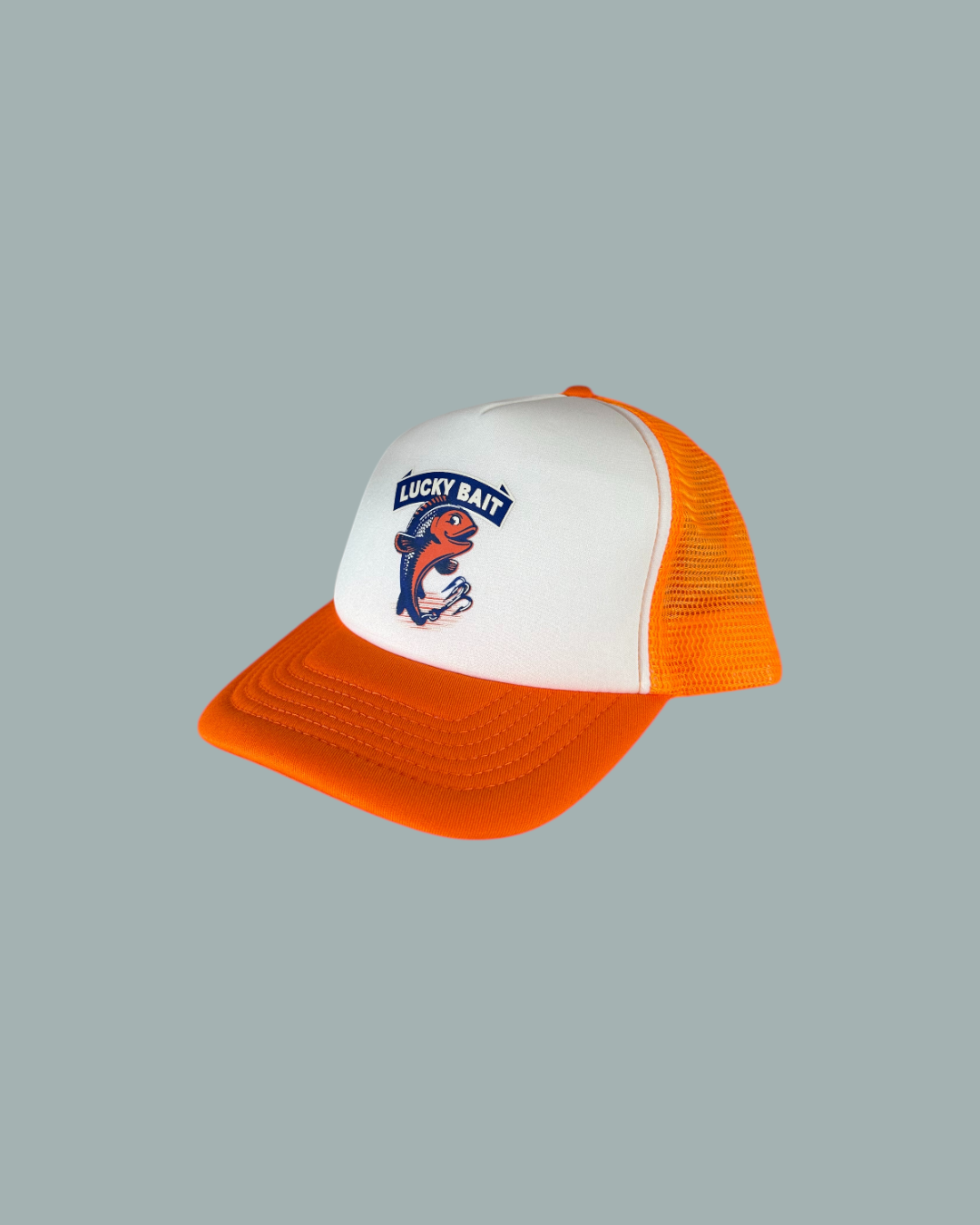 Keps Orange är en orange och vit trucker-keps med nätbaksida, en tecknad fisk och "Lucky Bait" text på framsidan. Visas mot en stålblå bakgrund.