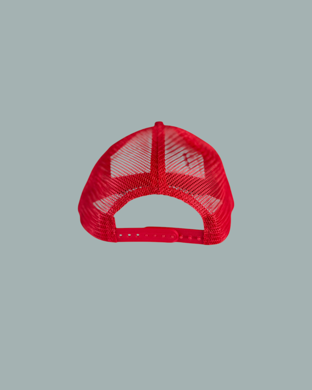 Keps Röd, en röd mesh-keps i trucker-stil, visas bakifrån med en justerbar plastknäppning med snäpplås. Visas mot en stålblå bakgrund.