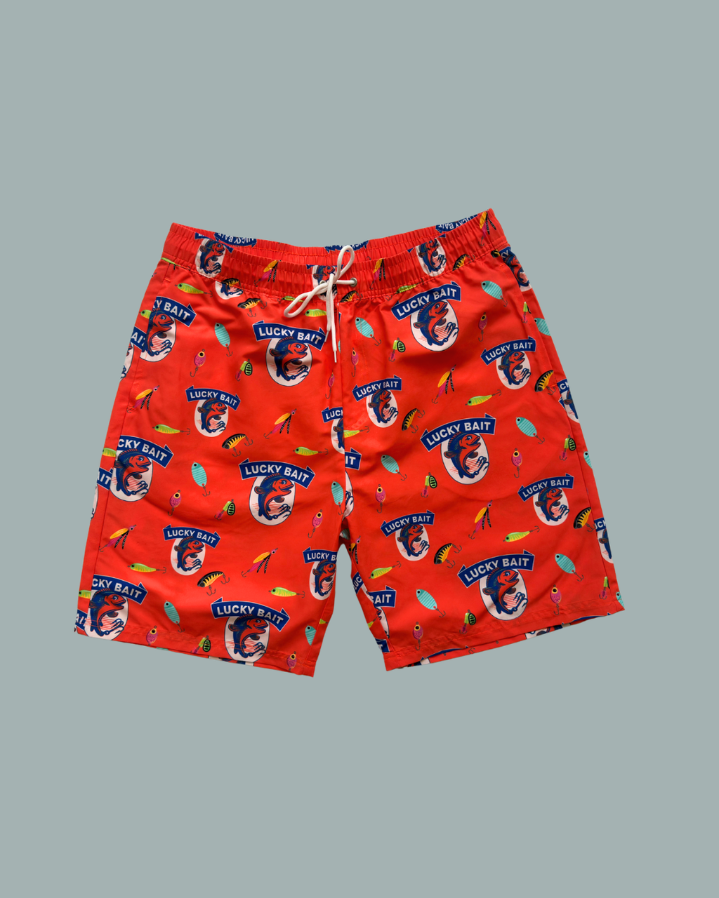 Lucky Bait Badbrallor från Lucky Bait Shop – färgglada badshorts för män med dragsko, dekorerade med fiskar, fiskekrokar och texten ”Lucky Bait” samt en tecknad fisk med solglasögon. Perfekta shorts för sommarens äventyr!.